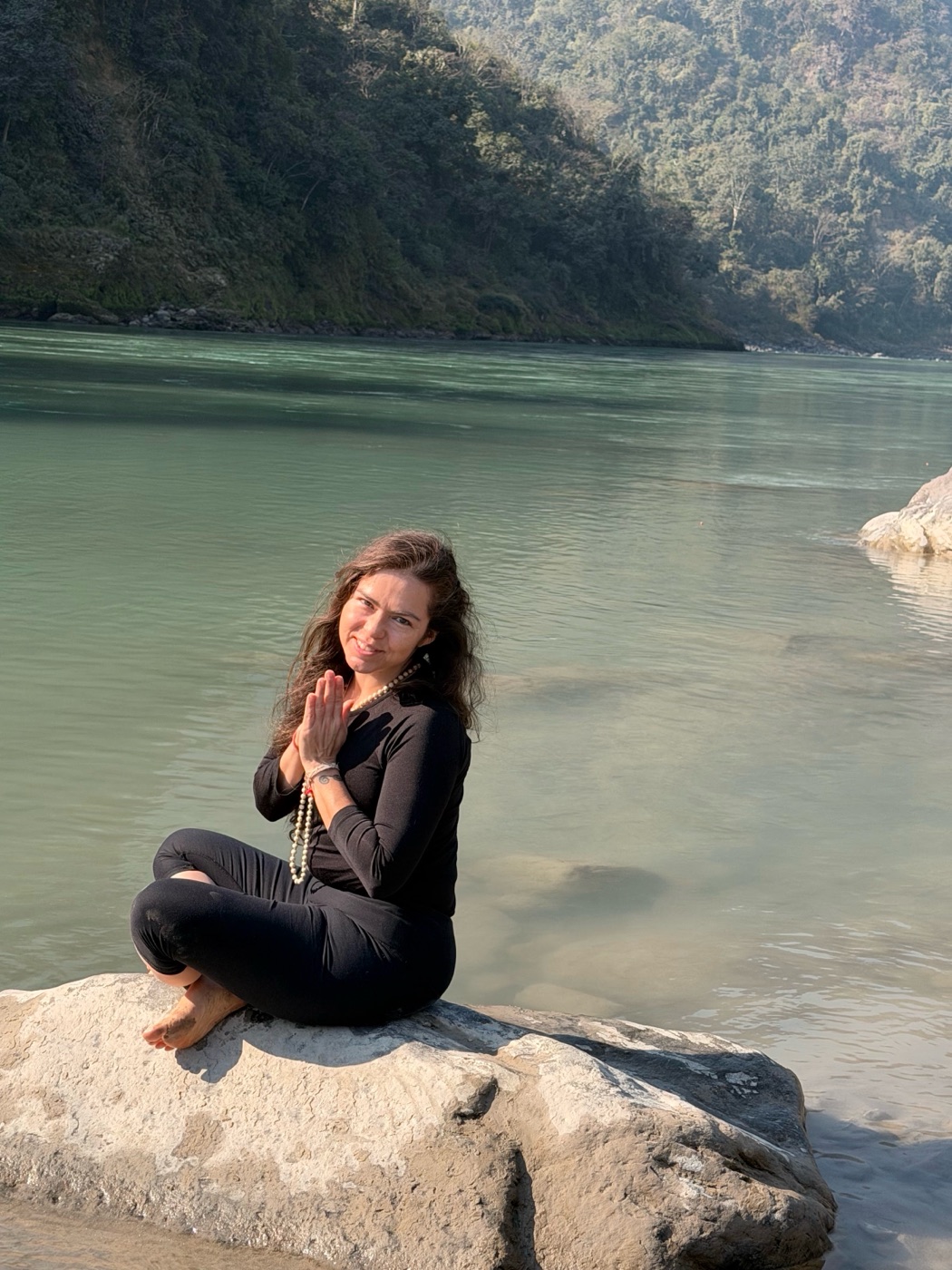 Kali sitting on a rock by a river in India with her hands at her heart