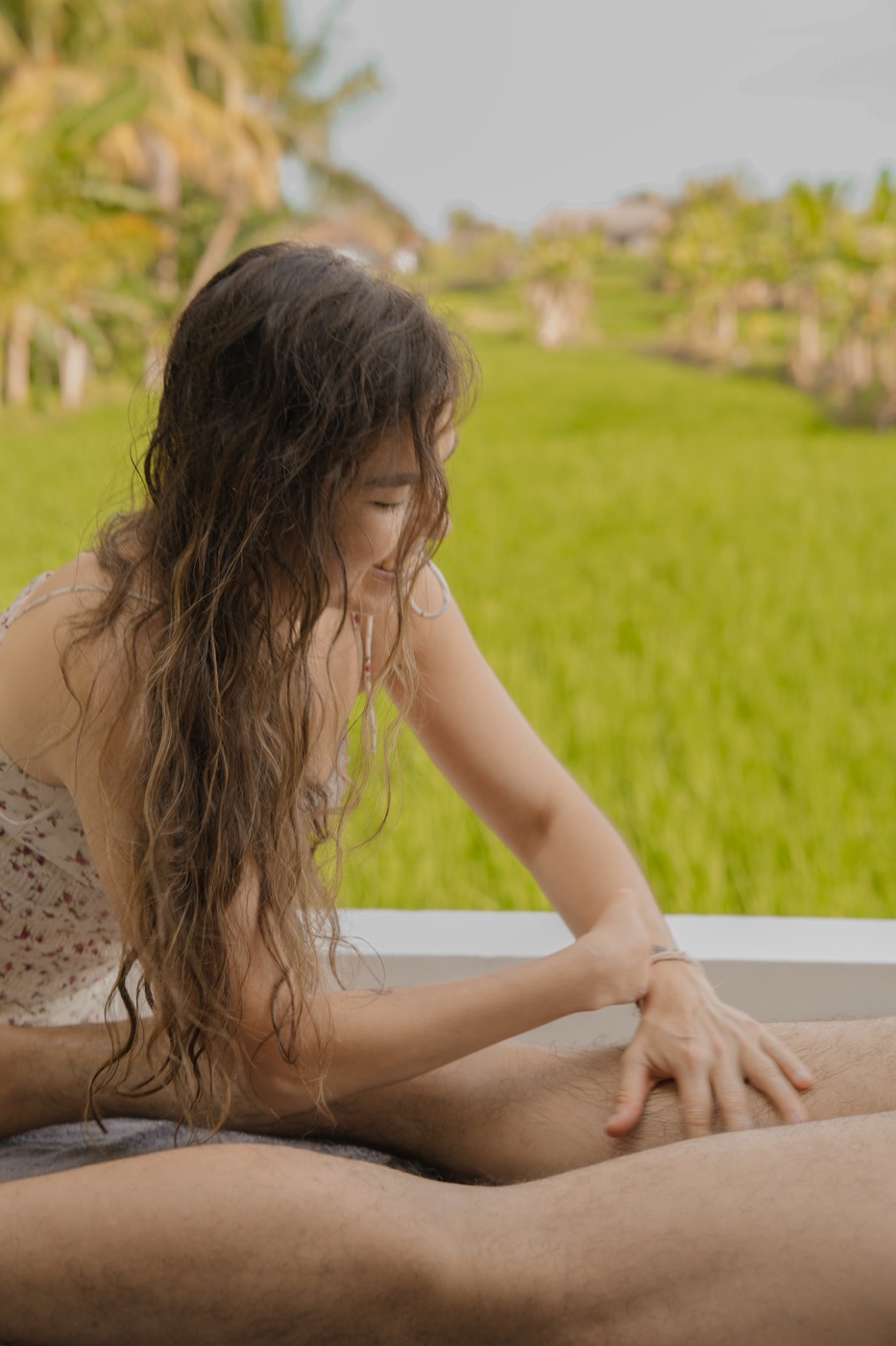 Kali giving a massage on a treatment table overlooking rice fields