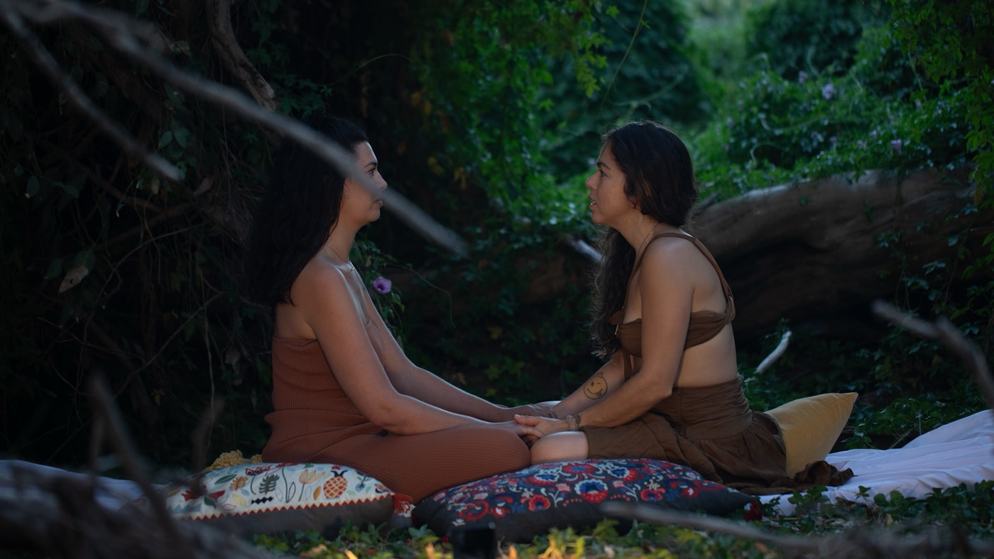 A tantra counselling session between two women seated on cushions outdoors