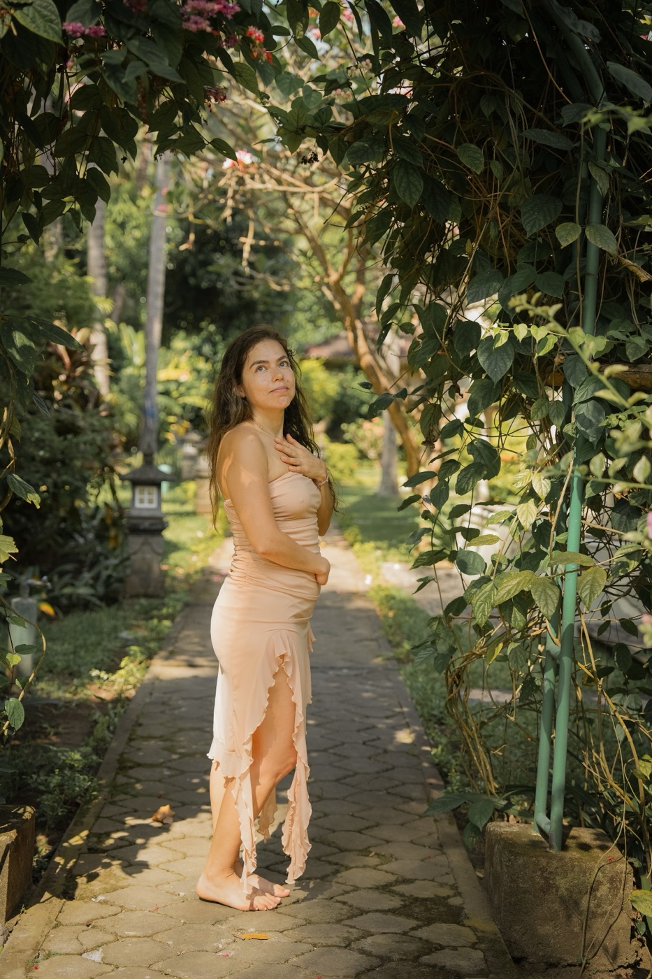 Kali walking along a garden path in a long dress